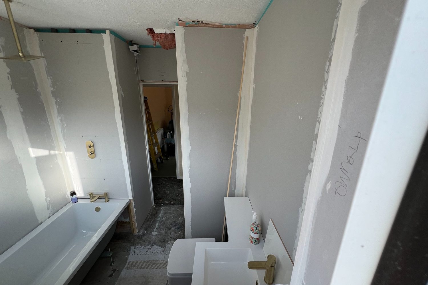A bathroom part way through: bath and brassware in, walls boarded and ready to tile