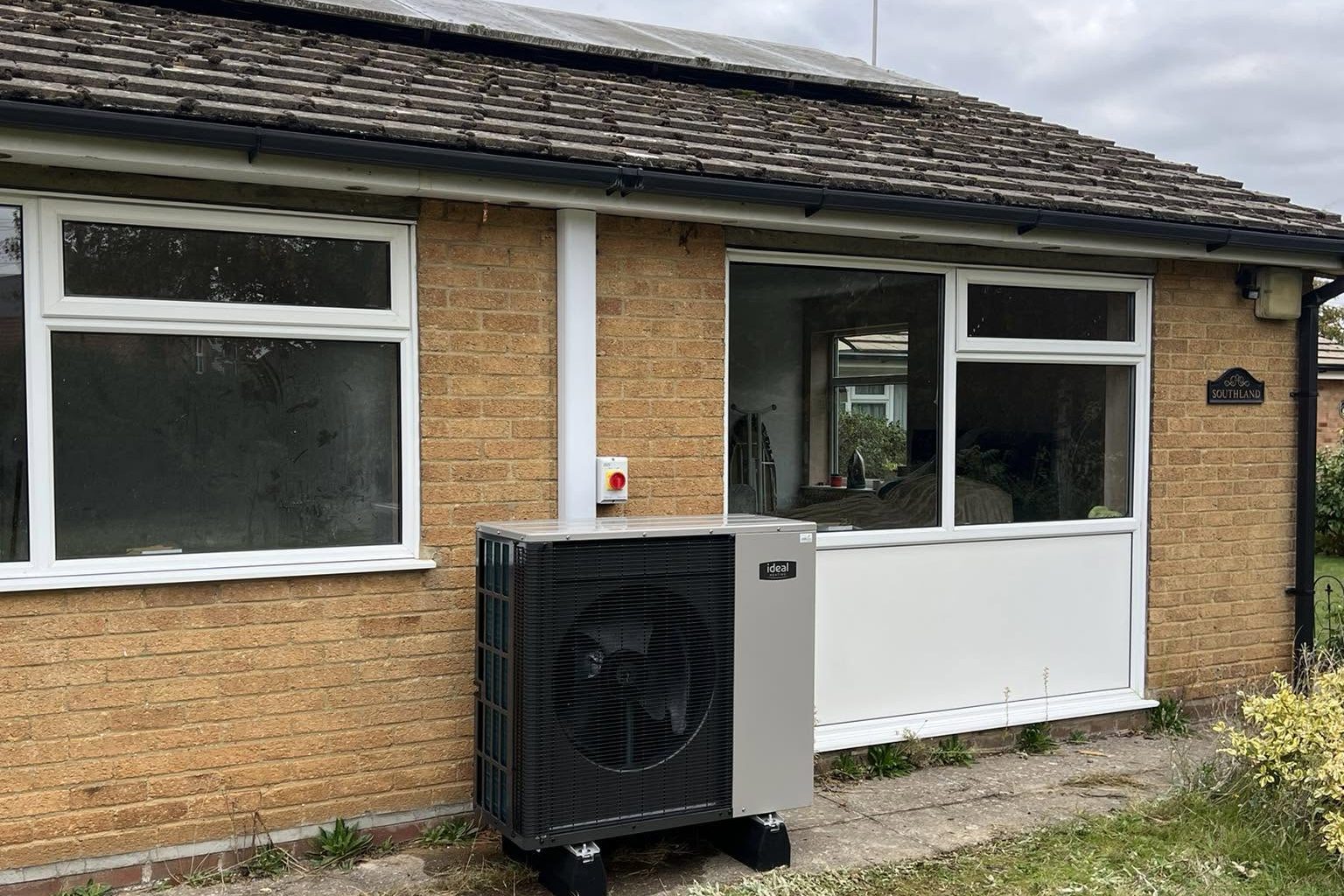 An installed air source heat pump seen from the garden