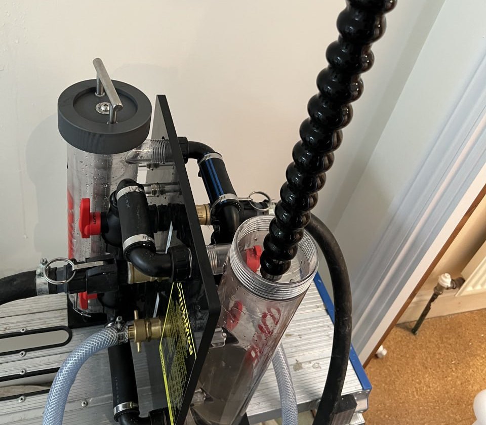 The clear magnetic filter chamber on the flushing rig with the magnet being withdrawn