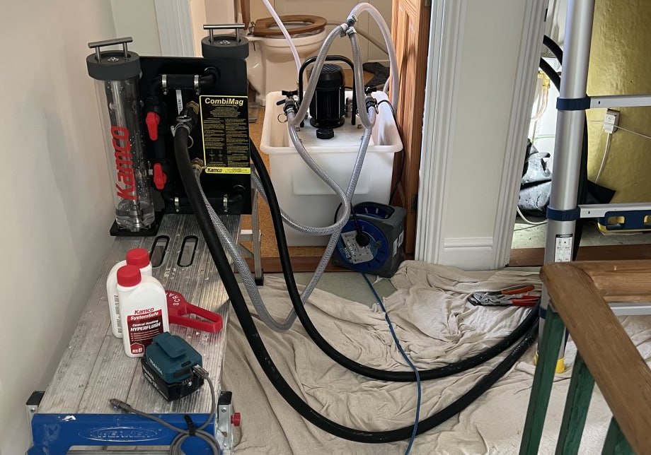 A Kamco flushing machine and magnetic filter set up on a landing with dust sheets down