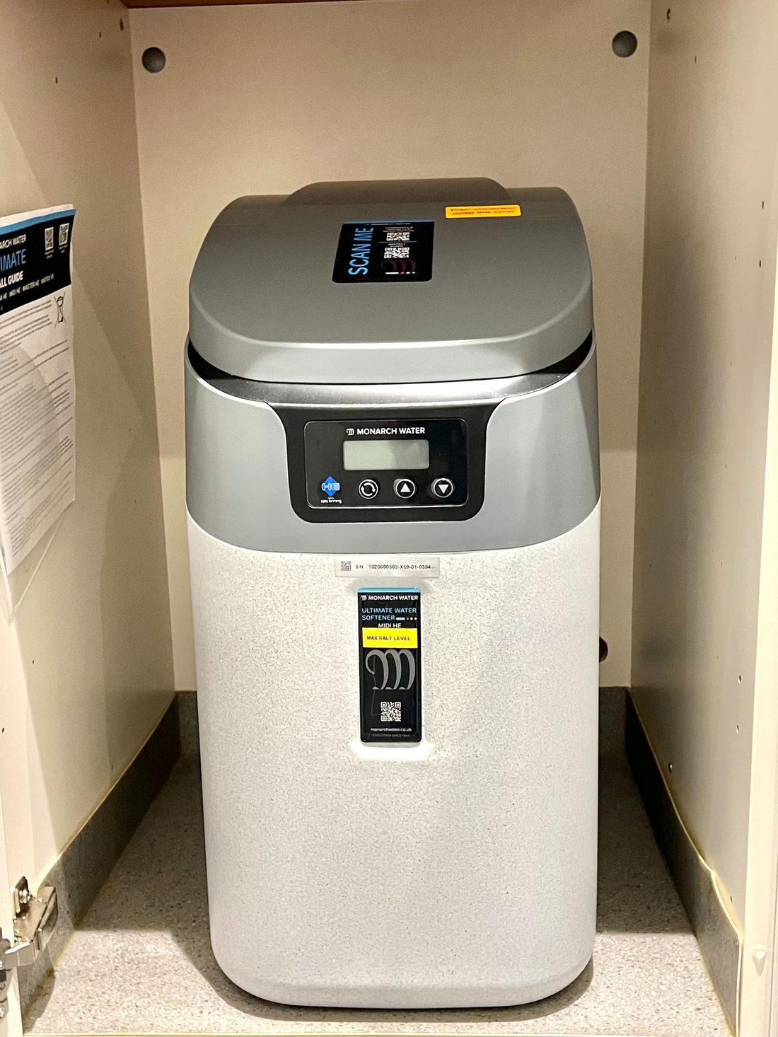 A water softener installed in a utility cupboard